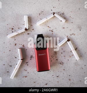 Vape cigarette électronique de l'appareil aspire breeze, comme alternative aux fumeurs de Marlboro cigarettes or brisé et dispersé sur le tabac texturé Blanc ba Banque D'Images