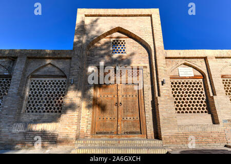 Façade de l'ancien caravansérail Ahmadjon, 19e siècle, avec porte en bois sculpté à Boukhara, Ouzbékistan. Banque D'Images