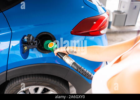 Une jeune femme mince avec des cheveux violets se remplit sa voiture avec de l'essence sans plomb, station service Shell Banque D'Images