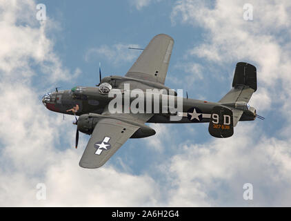 Une seconde guerre mondiale B-25 Mitchell bomber en vol contre un ciel partiellement nuageux. Banque D'Images