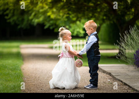 Une magnifique petite fille aux fleurs et page boy posing for chauds photos avant et après leurs rôles le jour du mariage, le mariage, le bonheur et l'amour Banque D'Images