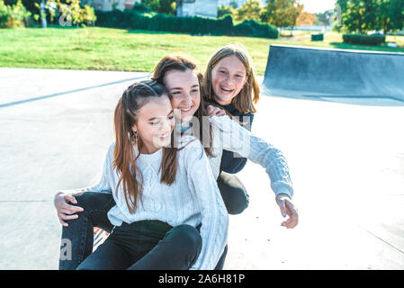 Trois écolières filles adolescents 13-15 ans, jour d'automne summer city, planche à roulettes se détendre après l'école en vacances. Les émotions de joie sont amusants Banque D'Images