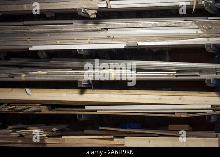 Des barres de métal et les arbres, en aluminium, ainsi que des planches en bois et de poutres apparentes en bois store lâche sur les étagères dans un atelier de charpentier Photo de la st Banque D'Images