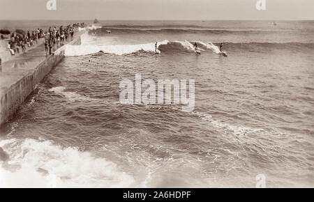 Équitation Les surfeurs de grosses vagues c1930s/1940s le long de la Californie Corona del Mar jetée, à côté des célèbres spots de surf maintenant connue sous le nom de cale dans Newport Beach. Banque D'Images