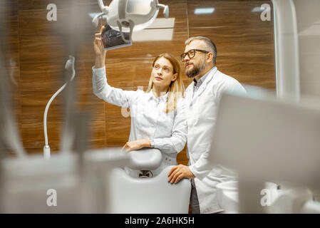 Deux dentistes examining x-ray d'une mâchoire humaine au cabinet dentaire Banque D'Images