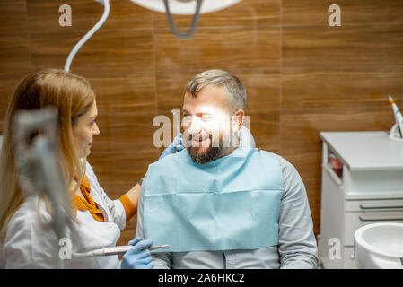 Femme dentiste et bel homme comme un patient lors d'une consultation médicale au cabinet dentaire Banque D'Images