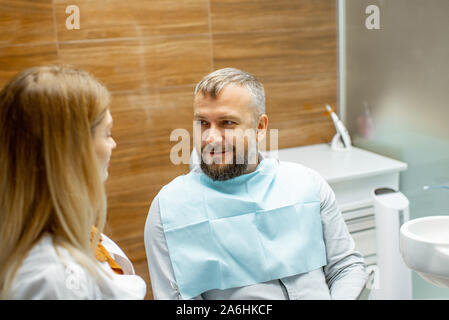 Femme dentiste et bel homme comme un patient lors d'une consultation médicale au cabinet dentaire Banque D'Images