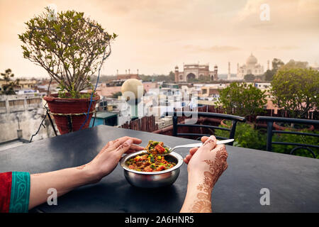 Femme mangeant des aliments traditionnels indiens au restaurant sur le toit avec vue sur le Taj Mahal à Agra, Uttar Pradesh, Inde Banque D'Images
