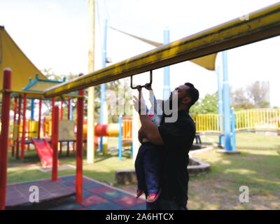 Tout-petits Asie un bon moment accroché au monkey bars avec son père. Banque D'Images