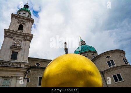 Stephan Balkenhol - Sphaera, une sculpture d'un homme sur une sphère dorée sur Kapitelplatz dans la ville de Salzburg, Autriche. La construction de la cathédrale à l'arrière-plan. Banque D'Images