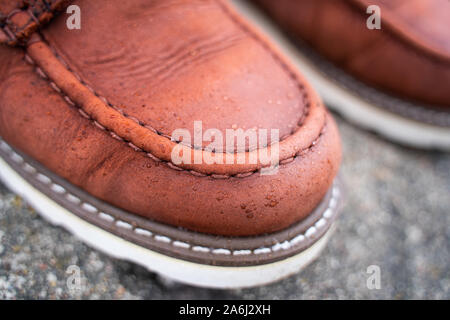 Gouttes d'eau sur des bottes de travail en cuir rouge close-up. Le concept d'imprégnation hydrofuge pour les chaussures en cuir Banque D'Images