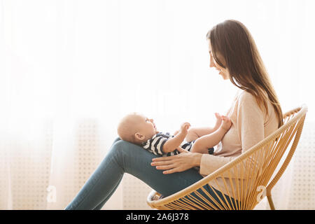 Femme assise au fauteuil en osier avec bébé nouveau-né sur lap Banque D'Images