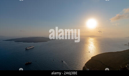 Fira, Grèce - 14 juillet 2019 : Le soleil se couche sur les îles de Santorin dans la mer Egée comme vu du haut des falaises de Fira Banque D'Images