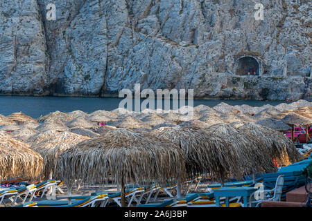 Kamari, Grèce - 14 juillet 2019 : Des rangées de paille couverts de parasols et de chaises longues à la plage de Kamari Banque D'Images