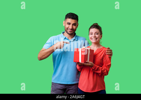 Meilleur cadeau pour elle. Portrait of happy couple dans des vêtements décontractés, man pointing at excited woman with gift box, à la satisfait et souriant à la caméra. je Banque D'Images