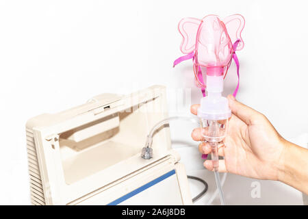 Ancien compresseur nébuliseur masque respiratoire avec inhalateur. L'appareil de pulvérisation Hand holding nébuliseur médicaux sur un fond blanc. Banque D'Images