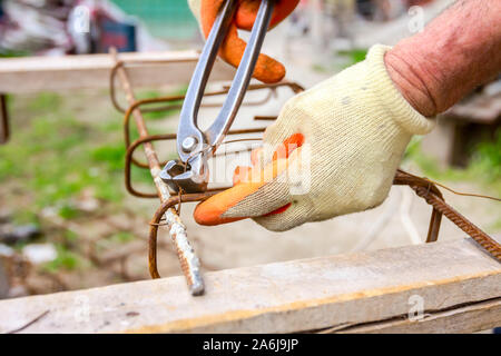 Travailleur est de lier avec du fil d'armature à l'aide de pinces, de faire un châssis poutre en béton pour renforcer. Banque D'Images