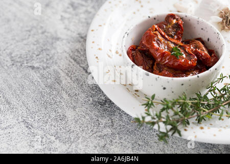 Les tomates séchées au soleil dans une assiette sur un fond de béton léger. Banque D'Images