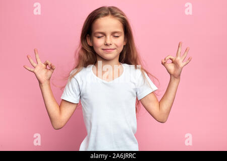 Adorable genre smiling girl avec de longs cheveux blonds faisant du yoga , fermer les yeux à l'expression rêveuse, élever les mains avec des gestes zen. Les soins de santé. hobby, Banque D'Images