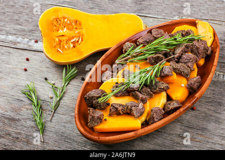 Tranches de citrouille cuite au four avec la viande en pot en argile. Repas d'automne avec le romarin et d'épices Banque D'Images