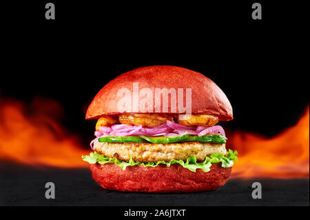 Burger rouge feu en flammes à l'arrière-plan sombre. Burger au poulet, cutlette bun rouge, l'oignon, les crevettes et d'avocat. Copy space Banque D'Images