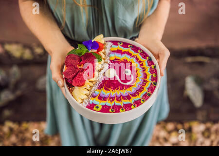 Jeune femme ayant un petit déjeuner méditerranéen, mange le petit-déjeuner tropical smoothie sain, bol de fruits tropicaux, décoré avec un motif de Banque D'Images