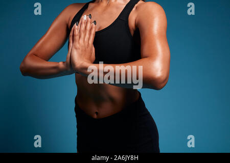 Close up de forte tnned musculaire transpiration woman practicing yoga, méditer. close up side view photo recadrée. isolated blue background, studio shot. l Banque D'Images