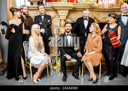 Photo de groupe mise en scène d'une élégante bien habillés les gens près de la cheminée joliment décorées avec arbre de Noël et présente au cours d'une célébration du Nouvel An Banque D'Images