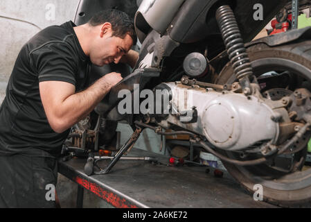 Mechanic repairing scooter moto dans garage de réparation . Banque D'Images