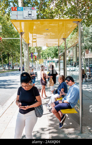 Barcelone Espagne,Catalogne El Poblenou,Avinguda Diagonal,avenue,arrêt de bus,abri,homme,femme,utilisant le téléphone cellulaire,passagers cavaliers navetteurs,attente,Hispani Banque D'Images