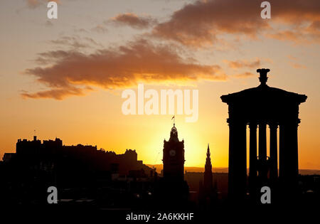 Calton Hill, Édimbourg, Royaume-Uni. 27 octobre 2019. Météo britannique. De soleil colorés sur le centre-ville en donnant une silhouette de Dugald Stewart Monument et château de Balmoral Hotel tour de l'horloge, un froid de 10 degrés. Banque D'Images