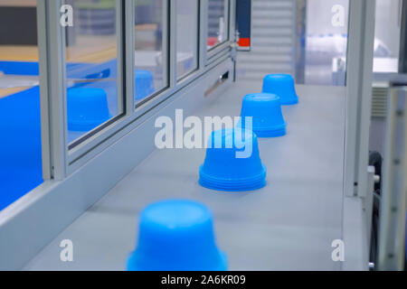 Pots bleus sur la courroie du convoyeur de machine de moulage par injection plastique Banque D'Images