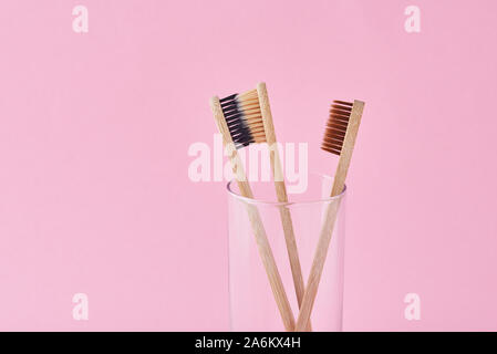 Trois brosses à dents en bambou en bois en verre sur fond rose. Concept d'hygiène dentaire Banque D'Images