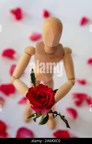 Marionnette en bois de main au cours d'une rose rouge Banque D'Images