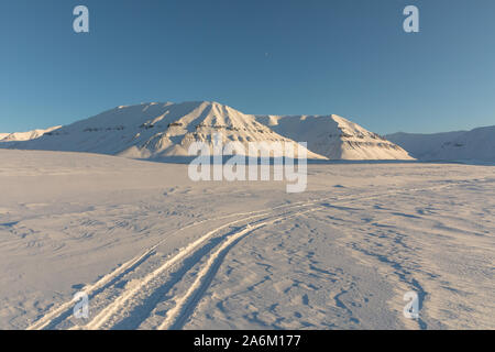 Les pistes de motoneige en hiver arctique paysage avec des montagnes enneigées sur Svalbard, Norvège Banque D'Images