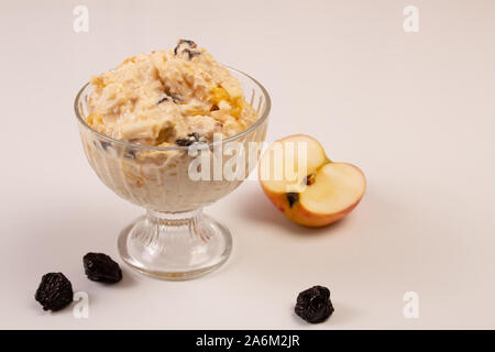 Salade de pomme, orange, avoine houblon et les pruneaux avec du miel dans une plaque de verre sur un fond blanc. Banque D'Images