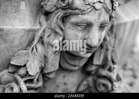 Plâtre Vintage visage d'une jeune femme avec des cheveux de feuilles sur le mur. Sculpture fissurée avec rugosité et fissures. La photographie en noir et blanc. Banque D'Images