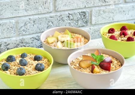 Délicieux doux petit déjeuner sain. Porridge avec différents fruits sur une table de cuisine en bois. Banque D'Images