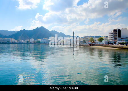 Bord de mer de la ville de Mascate, Oman, avec des bâtiments à l'avant-plan et entouré de montagnes derrière. Banque D'Images