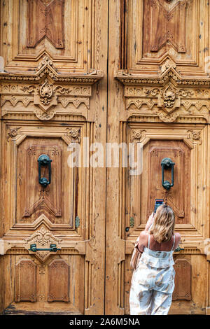 Valencia Espagne,Ciutat Vella,vieille ville,centre historique,Calle de la Paz,porte en bois sculpté ornée,knockers,femme,prise de photo smartphone,ES190829148 Banque D'Images