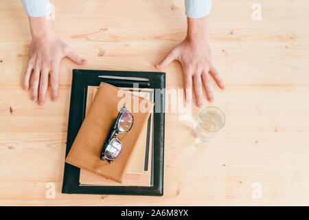 Businessman hands par verre d'eau, pile de cahiers, des stylos et des lunettes Banque D'Images