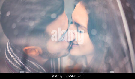 Jeune couple kissing under umbrella in rainy day - amoureux romantique ayant un moment de tendresse en plein air - les gens, l'amour et des relations concept Banque D'Images