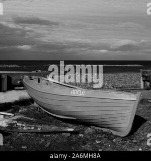 Adele : un bateau en bois, garé à Borth, Ceredigion, mi-pays de Galles. Photographié en noir et blanc. A l'horizon, mer calme et ciel couvert. Banque D'Images