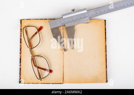 Étrier et vieux livre avec des lunettes sur un tableau blanc. Accessoires de l'atelier. Fond clair. Banque D'Images