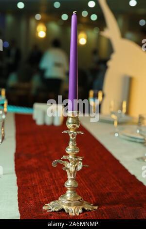 Des bougies allumées sur la table au restaurant . Violet pastel bougie en laiton antique chandelier ou candélabre sur fond flou avec l'exemplaire de l'espace. Banque D'Images