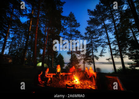 Amis de forêt près de feu au camping. Groupe de personnes sous ciel de nuit avec des étoiles de profiter de la nature vacances au camping. Banque D'Images