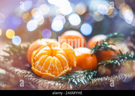 Mandarines Clémentines fraîches ou dans le panier sur la table en bois brun avec des branches d'arbres et lumières de Noël Banque D'Images