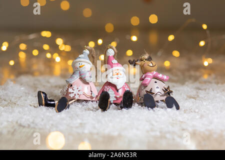 Figurines décoratives d'un thème de Noël. Ensemble de statuettes de santa, bonhomme de neige et les cerfs. Décoration d'arbre de Noël. Décor de fête, chaud bokeh lights Banque D'Images