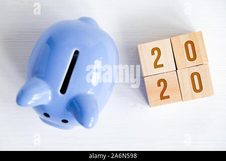 Tirelire bleu avec des numéros nouvelle année 2020 sur glaçons sur fond blanc. Vue de dessus. Concept de soins de l'épargne dans l'année à venir. Banque D'Images