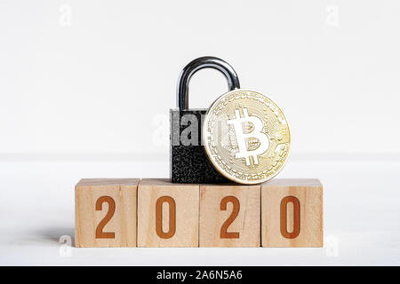 Chiffres 2020 sur les cubes en bois sur fond blanc à côté de monnaie bitcoin, mèche noire. Le concept de protection cryptocurrency dans la nouvelle année. Close up. Banque D'Images